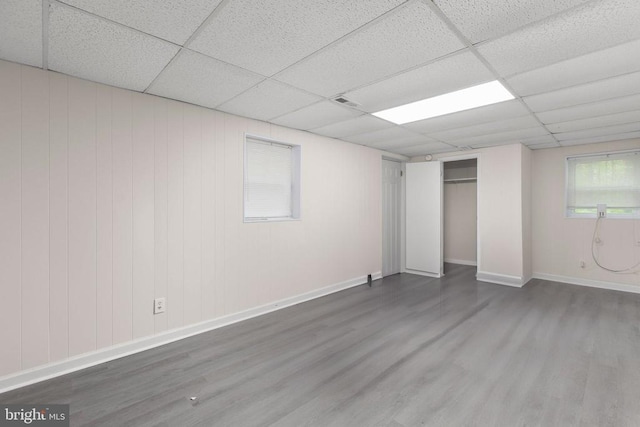 unfurnished bedroom with baseboards, a drop ceiling, a closet, and wood finished floors