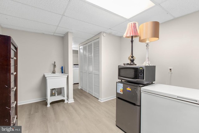 washroom with washer / dryer, baseboards, light wood finished floors, and a sink