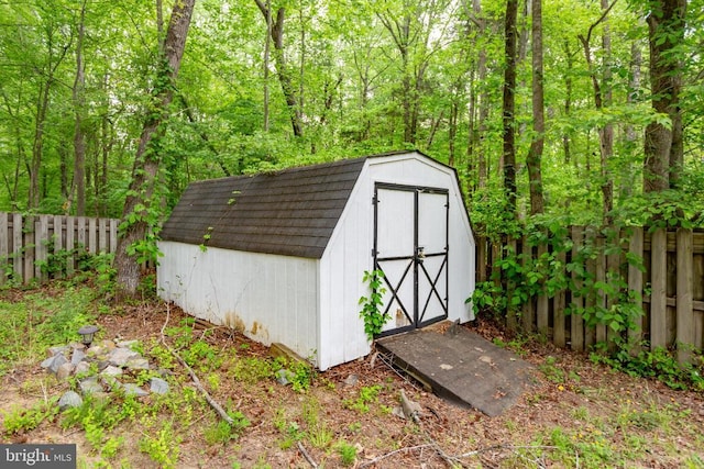 view of shed featuring fence and a view of trees