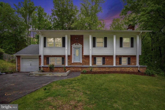 split foyer home featuring a chimney, brick siding, aphalt driveway, and an attached garage
