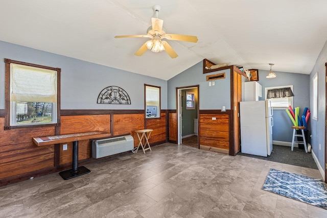 interior space with lofted ceiling, wainscoting, heating unit, ceiling fan, and wood walls