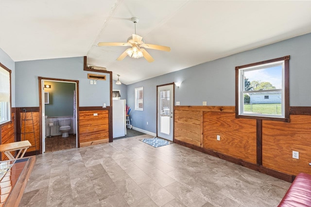 entryway featuring vaulted ceiling, a ceiling fan, and a wainscoted wall
