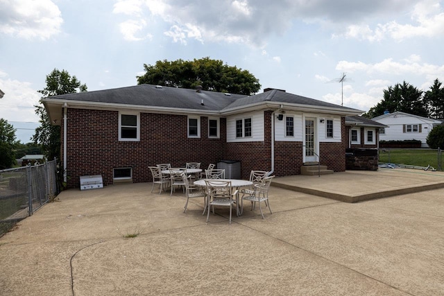 rear view of house featuring entry steps, fence, a patio, and brick siding