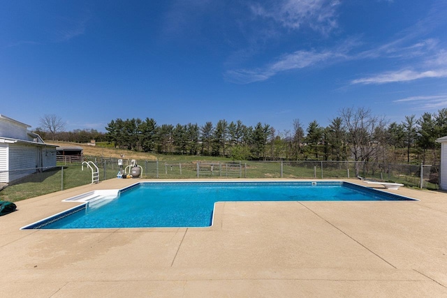 view of swimming pool with a patio area, a diving board, and view of wooded area