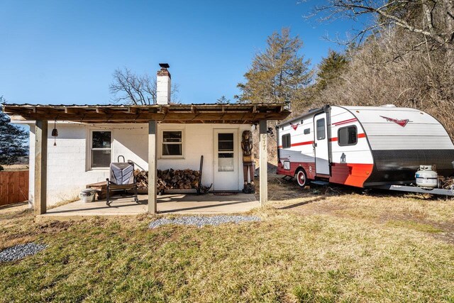 2077 Deerfield Valley Rd, West Augusta, VA 24485 - back of house with fence, a patio area, concrete block siding, a chimney, and a lawn