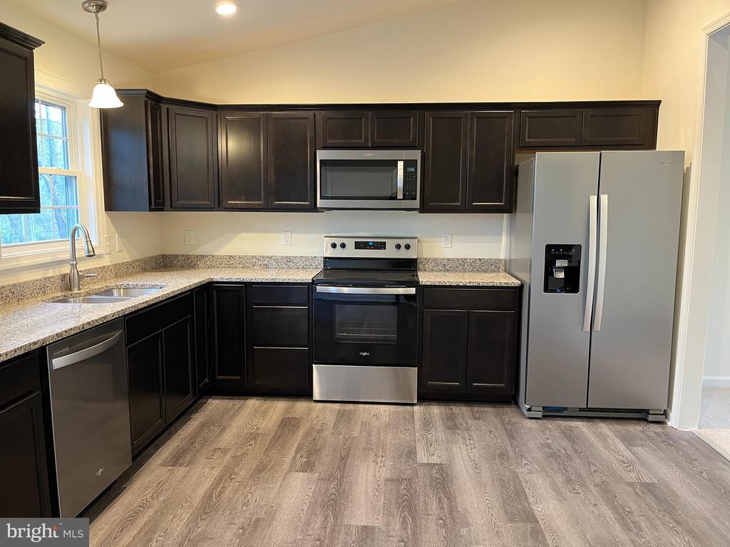 1219 Arrington Mountain Rd, Haywood, VA 22722 - kitchen with appliances with stainless steel finishes, vaulted ceiling, light wood-type flooring, decorative light fixtures, and light stone countertops