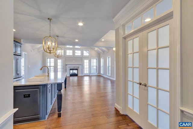 kitchen with pendant lighting, light hardwood / wood-style flooring, stainless steel refrigerator, a high end fireplace, and light stone countertops