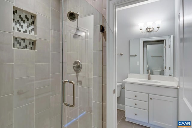 bathroom with a shower with door, vanity, tile patterned floors, and toilet