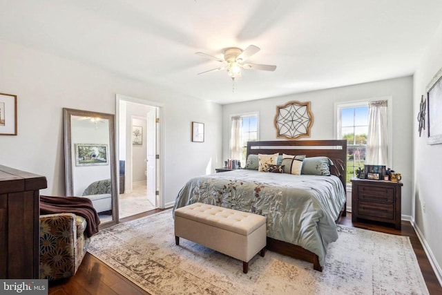 bedroom featuring wood finished floors, baseboards, ceiling fan, and ensuite bath