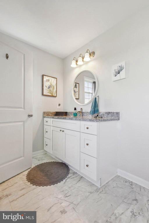 bathroom featuring marble finish floors, vanity, and baseboards