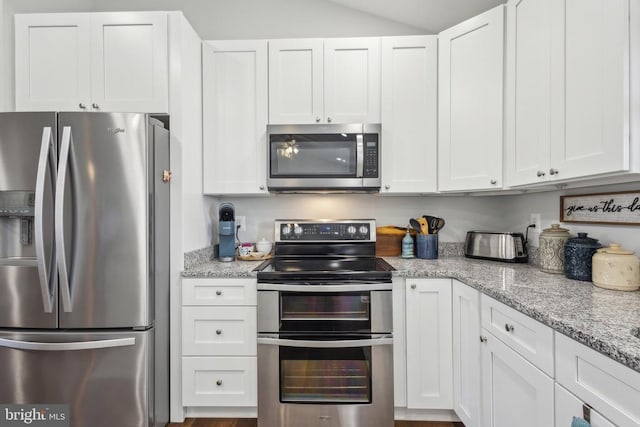 kitchen with appliances with stainless steel finishes, white cabinetry, and light stone counters