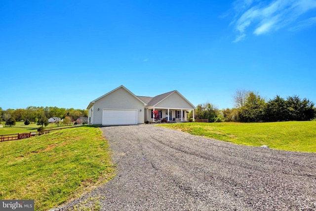 ranch-style house featuring a garage, a front lawn, covered porch, and gravel driveway