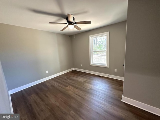 empty room with a ceiling fan, baseboards, and dark wood-type flooring