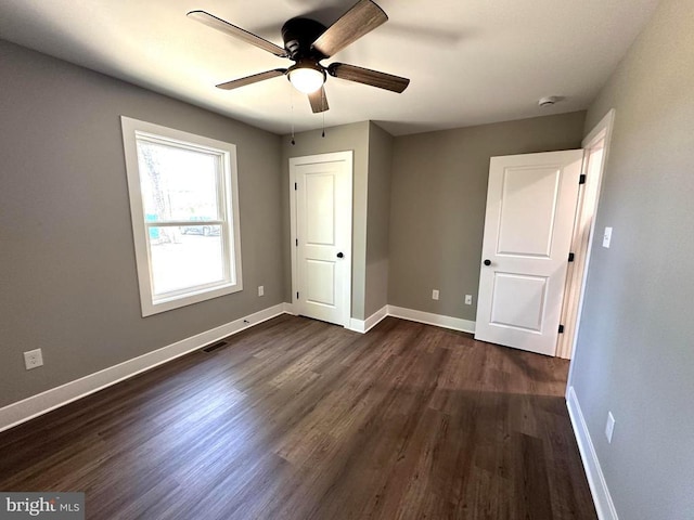 unfurnished bedroom featuring dark wood-type flooring, baseboards, visible vents, and ceiling fan