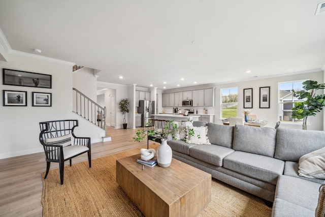living room with ornamental molding, light wood finished floors, baseboards, stairs, and recessed lighting