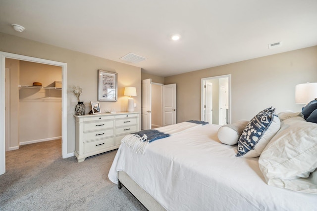 bedroom with light carpet, a spacious closet, baseboards, a closet, and ensuite bath