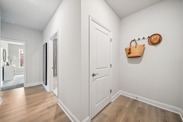 corridor with light wood finished floors and baseboards
