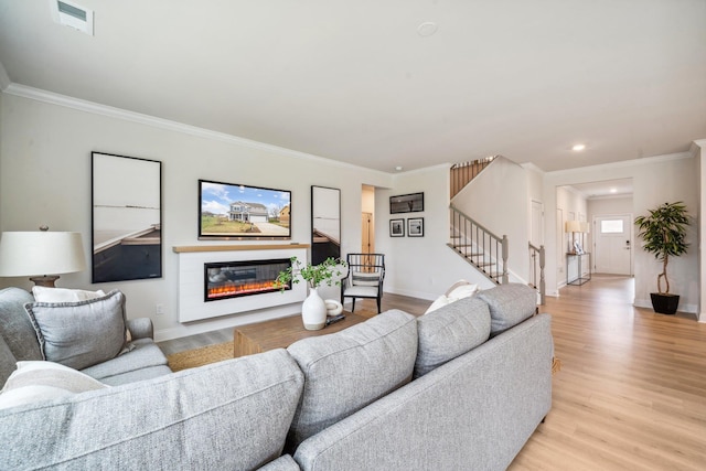 living room with stairway, light wood-style floors, a glass covered fireplace, recessed lighting, and baseboards