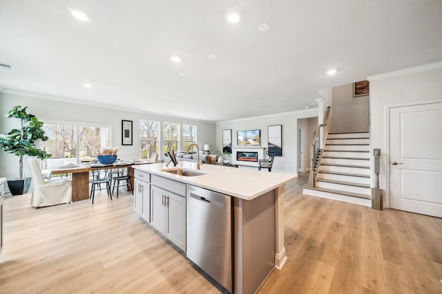 kitchen featuring stainless steel dishwasher, crown molding, a sink, an island with sink, and recessed lighting