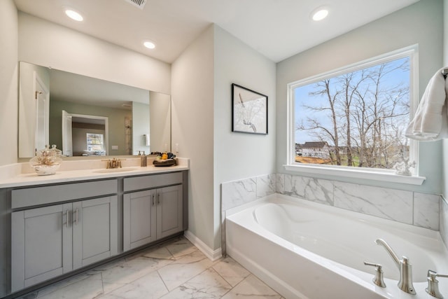 bathroom with marble look tiles, a bath, vanity, recessed lighting, and baseboards