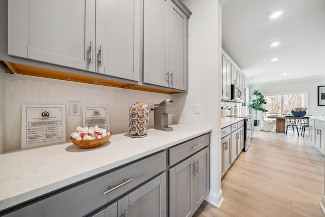 kitchen with gray cabinetry, stainless steel appliances, light wood-style floors, recessed lighting, and crown molding