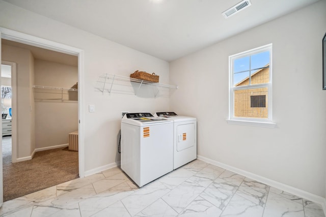 clothes washing area with washing machine and clothes dryer, light marble finish flooring, and baseboards