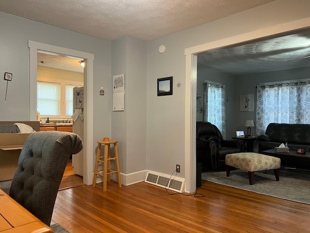 office area featuring hardwood / wood-style floors, healthy amount of natural light, a textured ceiling, and baseboards