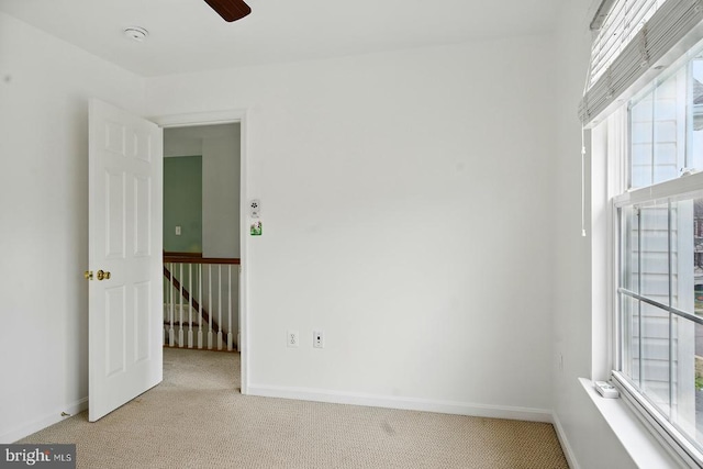 spare room with light colored carpet, plenty of natural light, and baseboards