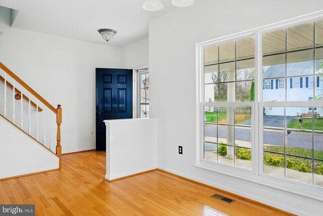 foyer entrance with baseboards, light wood-style floors, and stairway