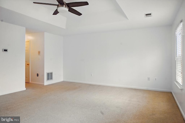 spare room featuring light carpet, a ceiling fan, and baseboards