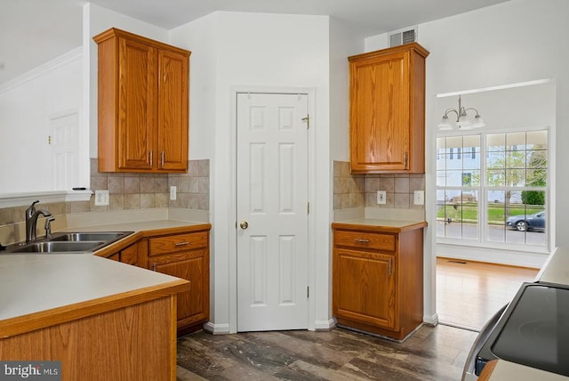 kitchen featuring a sink, range with electric stovetop, and brown cabinets