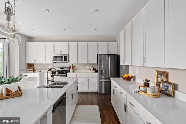 kitchen with appliances with stainless steel finishes, a sink, light countertops, white cabinets, and dark wood-type flooring