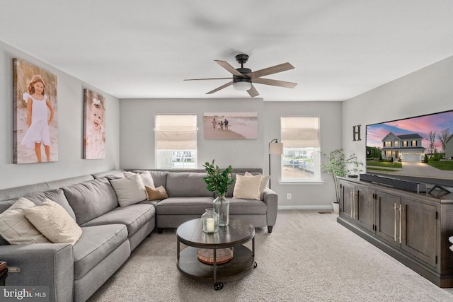 living room featuring ceiling fan, light carpet, and baseboards