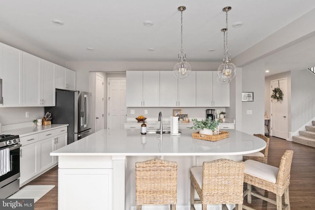 kitchen with appliances with stainless steel finishes, light countertops, dark wood-style flooring, a sink, and recessed lighting