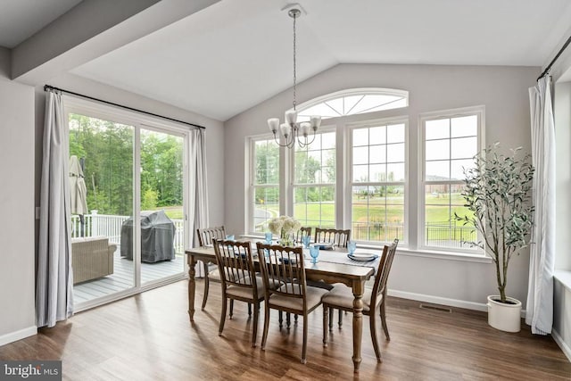 dining area featuring healthy amount of natural light, a chandelier, vaulted ceiling, and wood finished floors