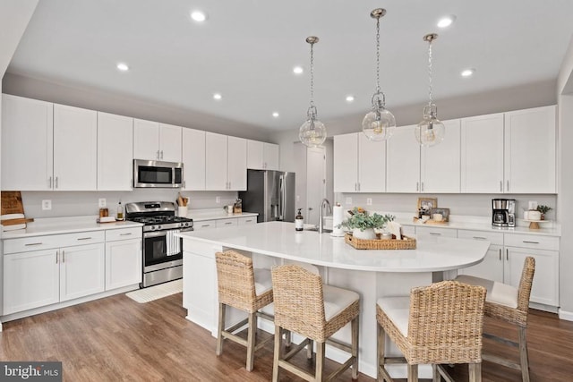 kitchen with stainless steel appliances, a kitchen breakfast bar, light countertops, and recessed lighting