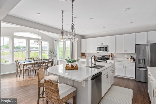 kitchen featuring appliances with stainless steel finishes, a sink, light countertops, dark wood finished floors, and recessed lighting