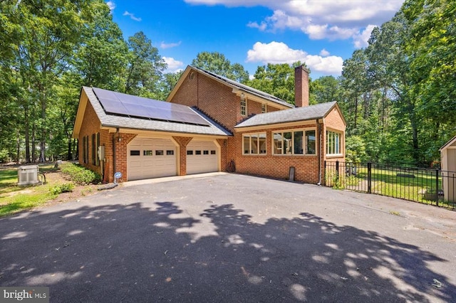 100 River Bend Rd W, Fredericksburg, VA 22407 - view of front facade featuring brick siding, roof mounted solar panels, driveway, a chimney, and an attached garage
