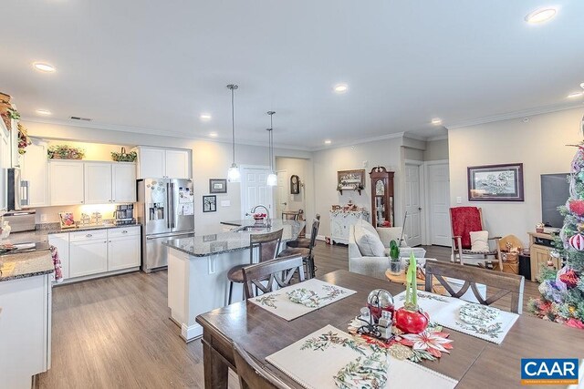 dining area featuring crown molding, light wood-style flooring, visible vents, and recessed lighting