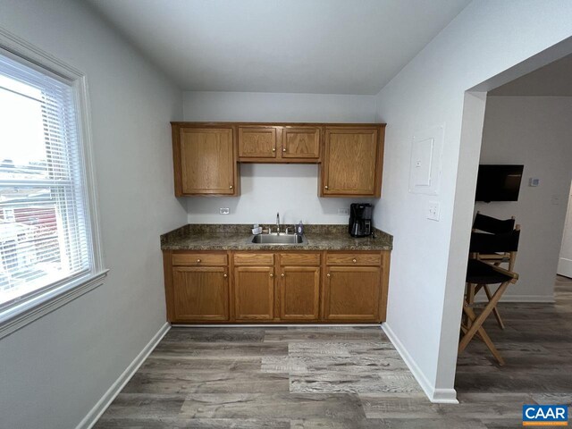 301 7th St SW, Charlottesville, VA 22903 - kitchen with a sink, brown cabinetry, dark countertops, and a healthy amount of sunlight