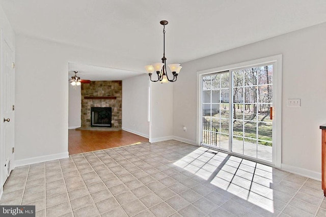 unfurnished dining area with light tile patterned floors, baseboards, ceiling fan with notable chandelier, and a stone fireplace