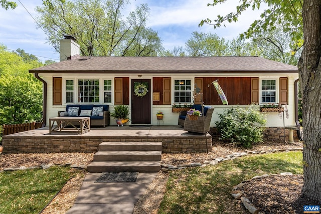 ranch-style home featuring a chimney, outdoor lounge area, and a shingled roof