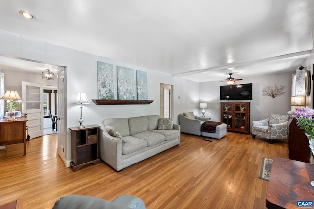 living room with light wood-type flooring, ceiling fan, and a chandelier