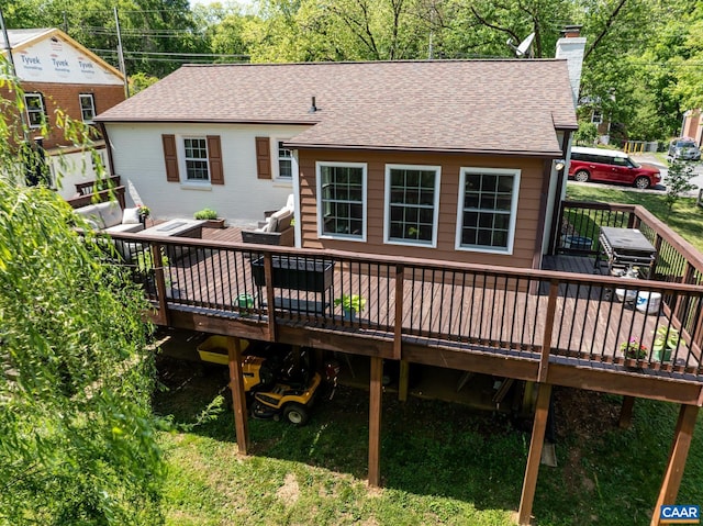 back of house with a chimney, a wooden deck, and a shingled roof