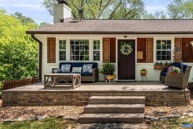 view of exterior entry featuring a chimney, a shingled roof, and a porch