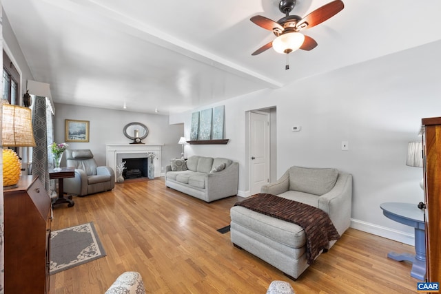 living area with ceiling fan, baseboards, light wood-style flooring, and a fireplace with flush hearth