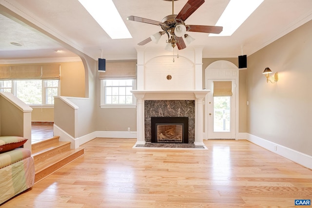 unfurnished living room featuring crown molding, a skylight, a wealth of natural light, and a ceiling fan