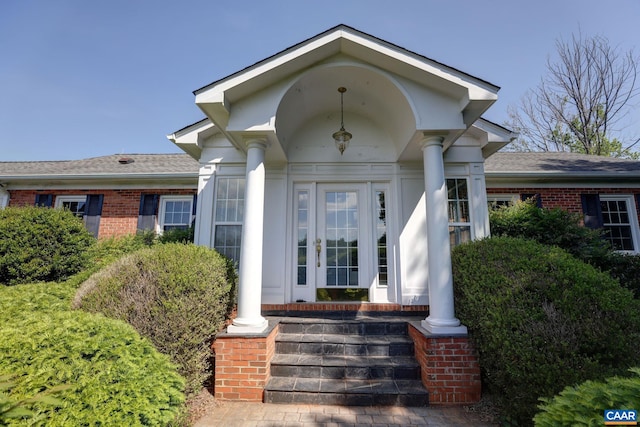 doorway to property with a porch and brick siding