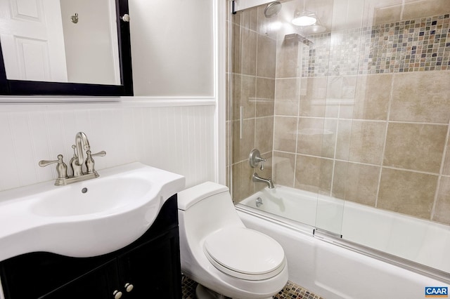 full bath featuring enclosed tub / shower combo, vanity, toilet, and wainscoting