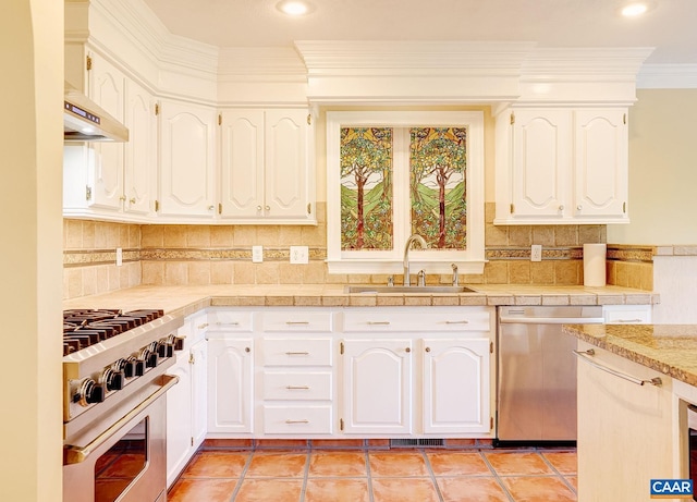 kitchen with under cabinet range hood, ornamental molding, a sink, white cabinetry, and appliances with stainless steel finishes
